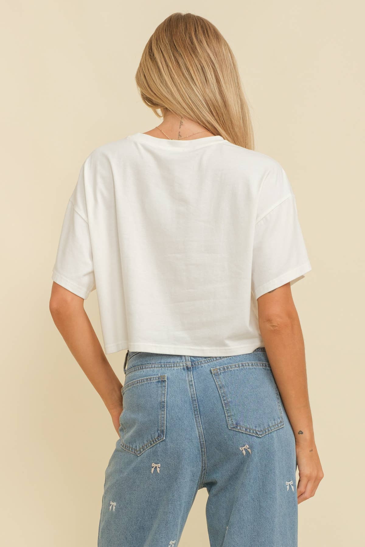 Woman wearing a white crop top with an American flag design on a beige background