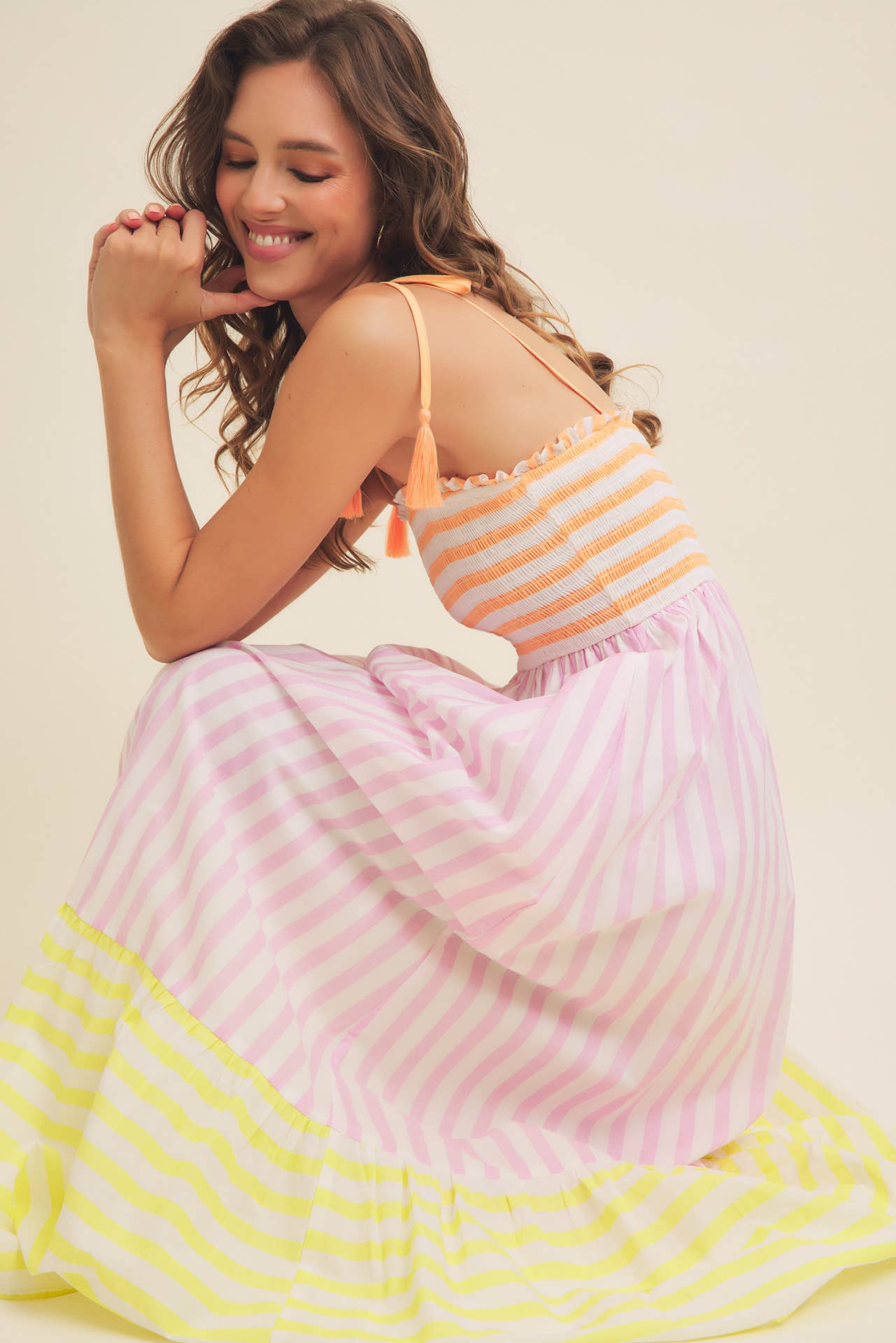 Woman wearing a colorful striped dress with a plain background