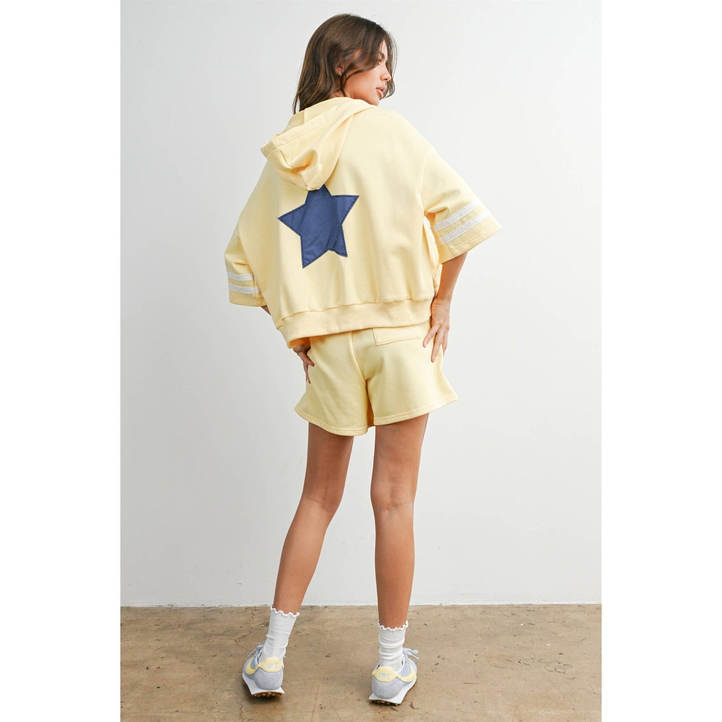 Person wearing a yellow outfit with a blue star on a plain background