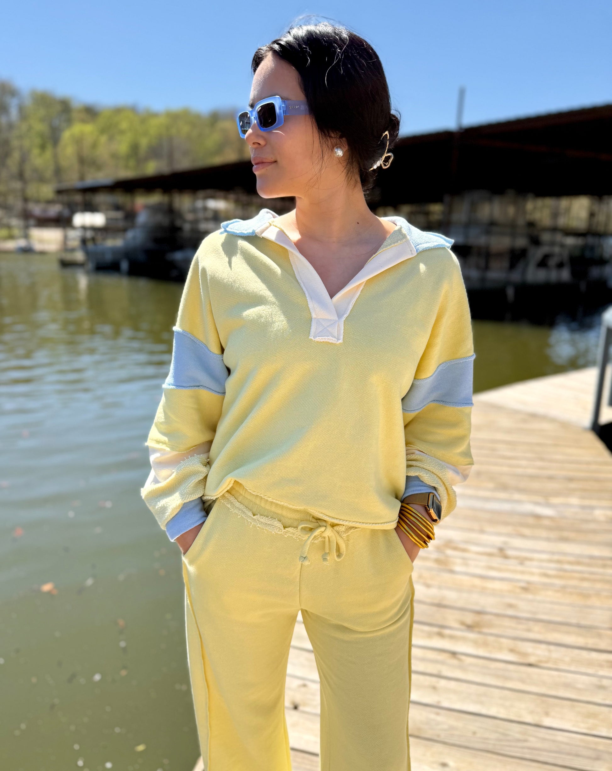 Person wearing a yellow outfit standing on a dock by a body of water.
