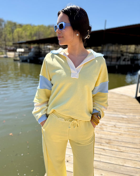 Person wearing a yellow outfit standing on a dock by a body of water.