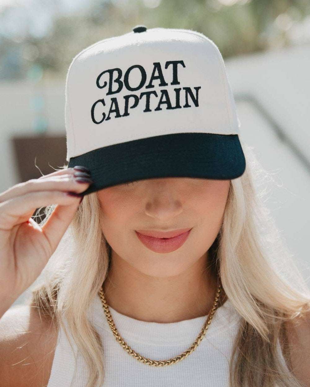 Person wearing a 'BOAT CAPTAIN' cap outdoors