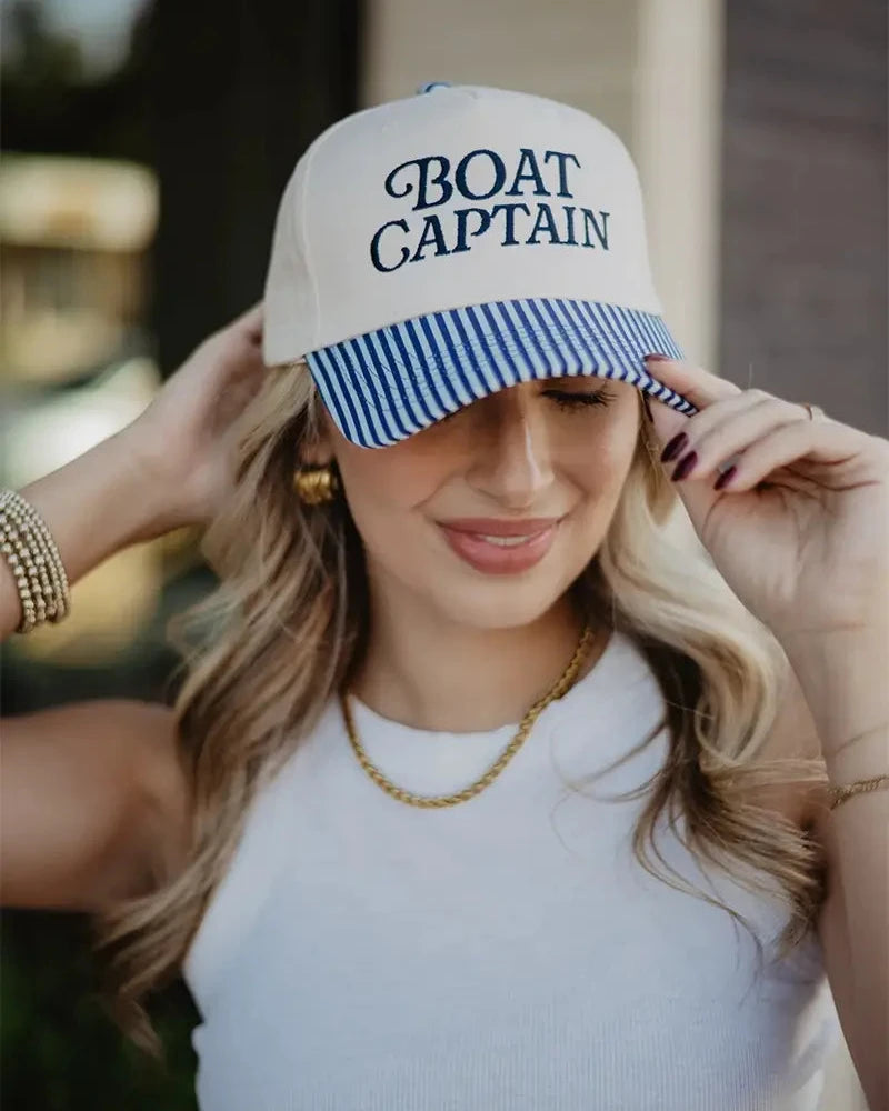 Woman wearing a cap with 'BOAT CAPTAIN' text outdoors