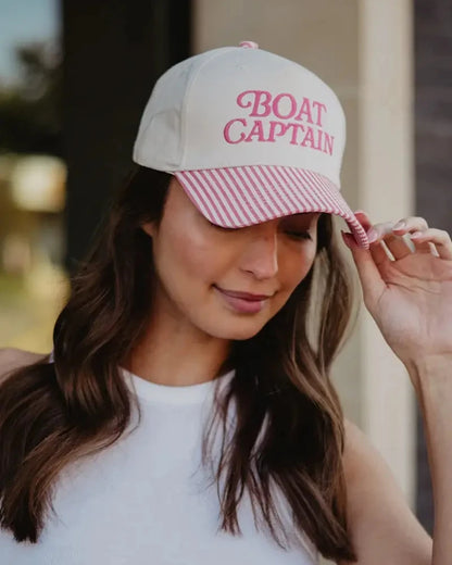 Woman wearing a cap with 'BOAT CAPTAIN' text, blurred background