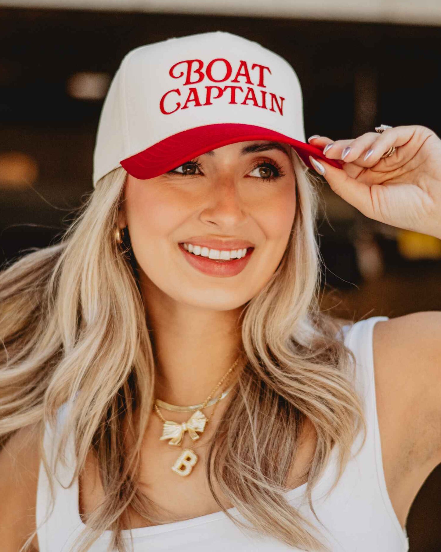 Woman wearing a 'BOAT CAPTAIN' cap and smiling.