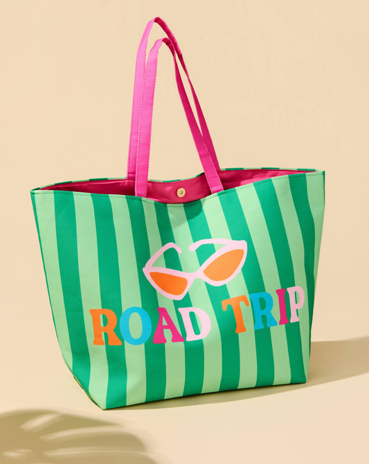 Green and pink striped tote bag with 'ROAD TRIP' text and sunglasses design on a beige background