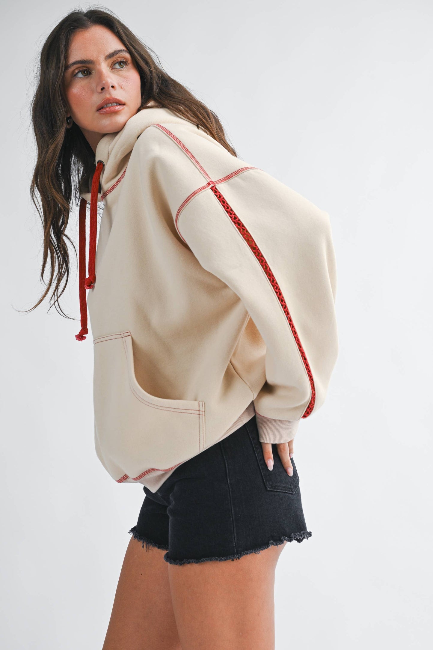 Woman wearing a beige hoodie with red accents on a white background