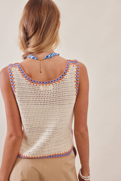 Woman wearing a crochet top with colorful trim on a plain background