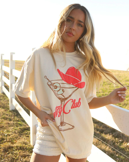 Woman wearing a white t-shirt with a red and brown graphic design outdoors.