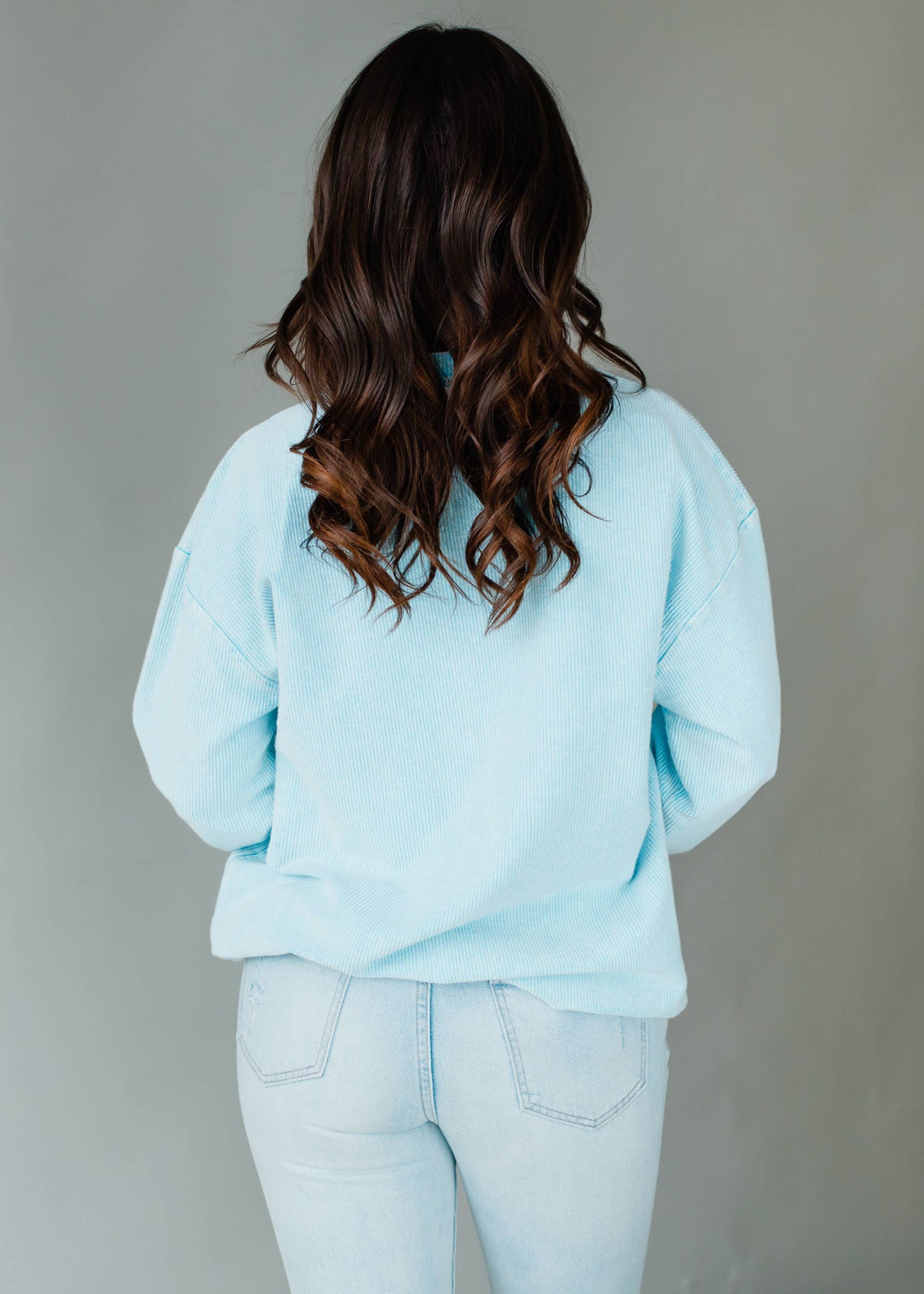 Woman wearing a light blue sweatshirt with 'DAY DRINKING' text against a gray background