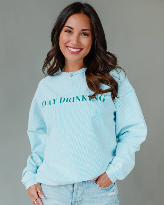 Woman wearing a light blue sweatshirt with 'DAY DRINKING' text against a gray background