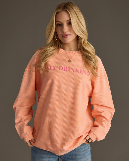 Woman wearing a peach sweatshirt with 'DAY DRINKING' text on a gray background