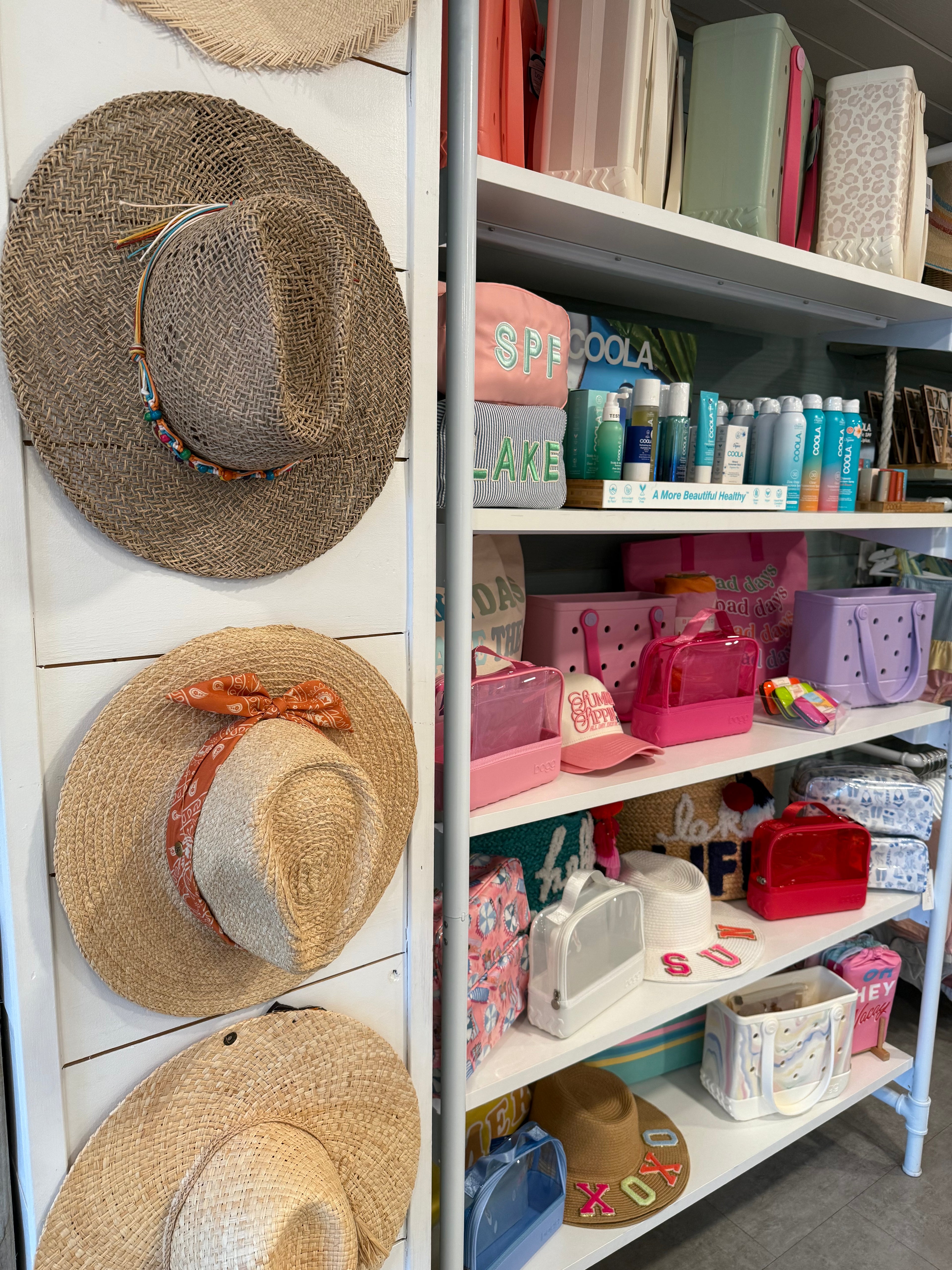 Three straw hats on a white surface with an open drawer filled with stationery items in the background.