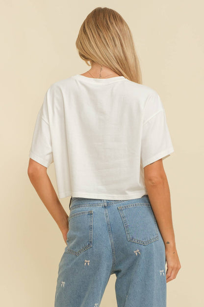 Woman wearing a white crop top with an American flag design on a beige background