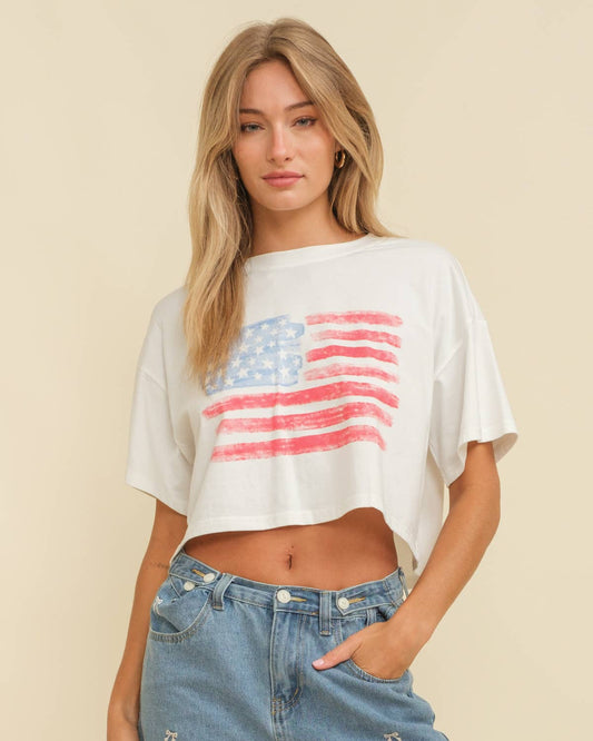 Woman wearing a white crop top with an American flag design on a beige background