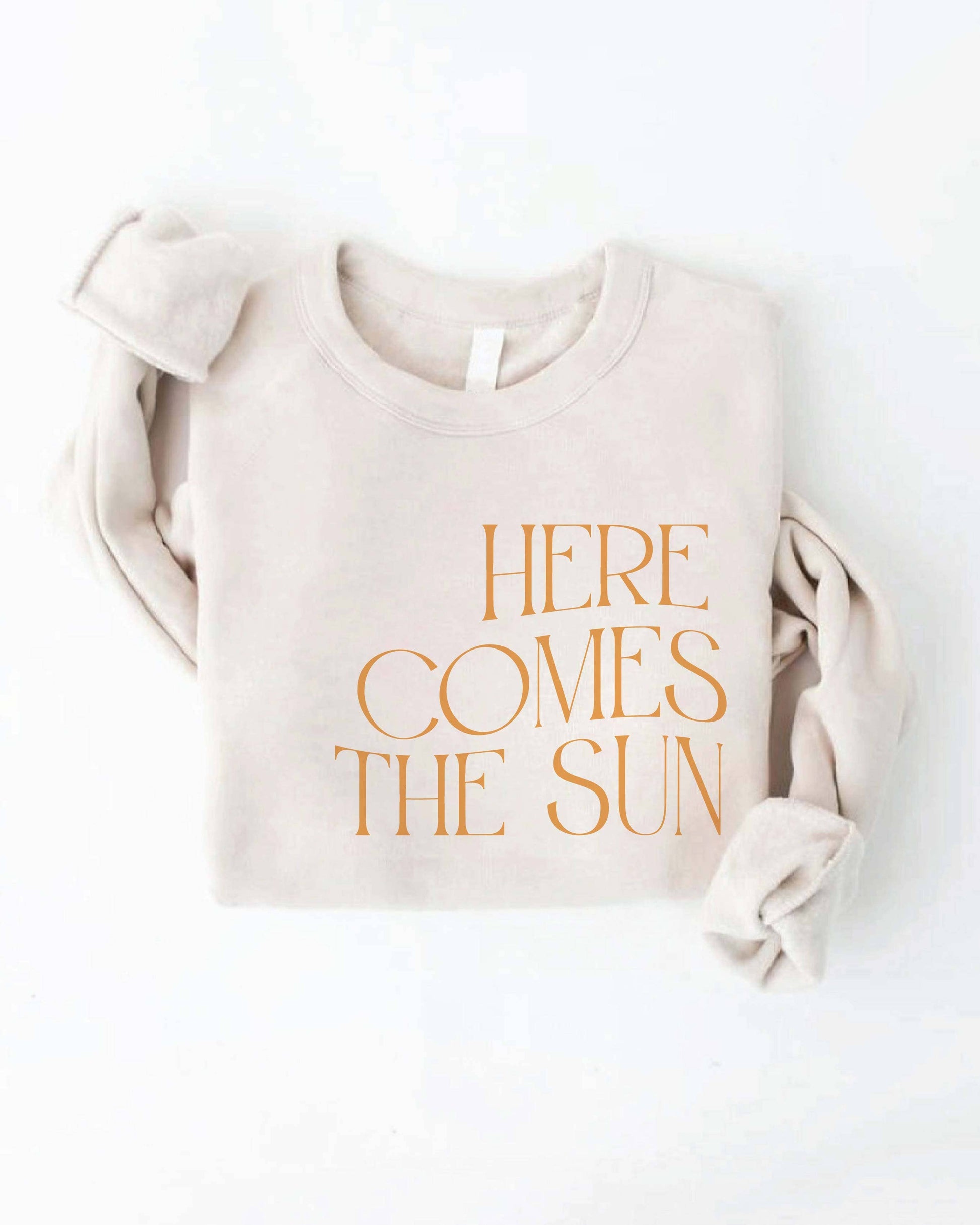 Beige sweatshirt with 'Here Comes the Sun' text on a white background