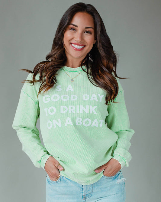 Woman wearing a light green sweatshirt with text, standing against a plain background