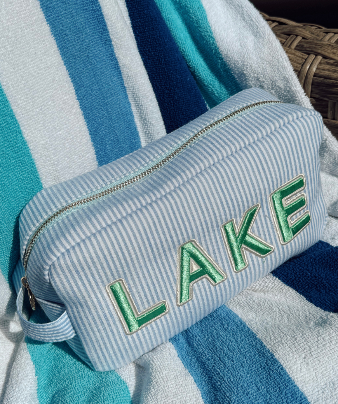 Striped towel with 'LAKE' embroidery on a blue and white striped background