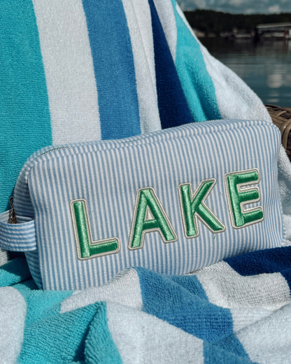 Striped towel with 'LAKE' embroidery on a blue and white striped background