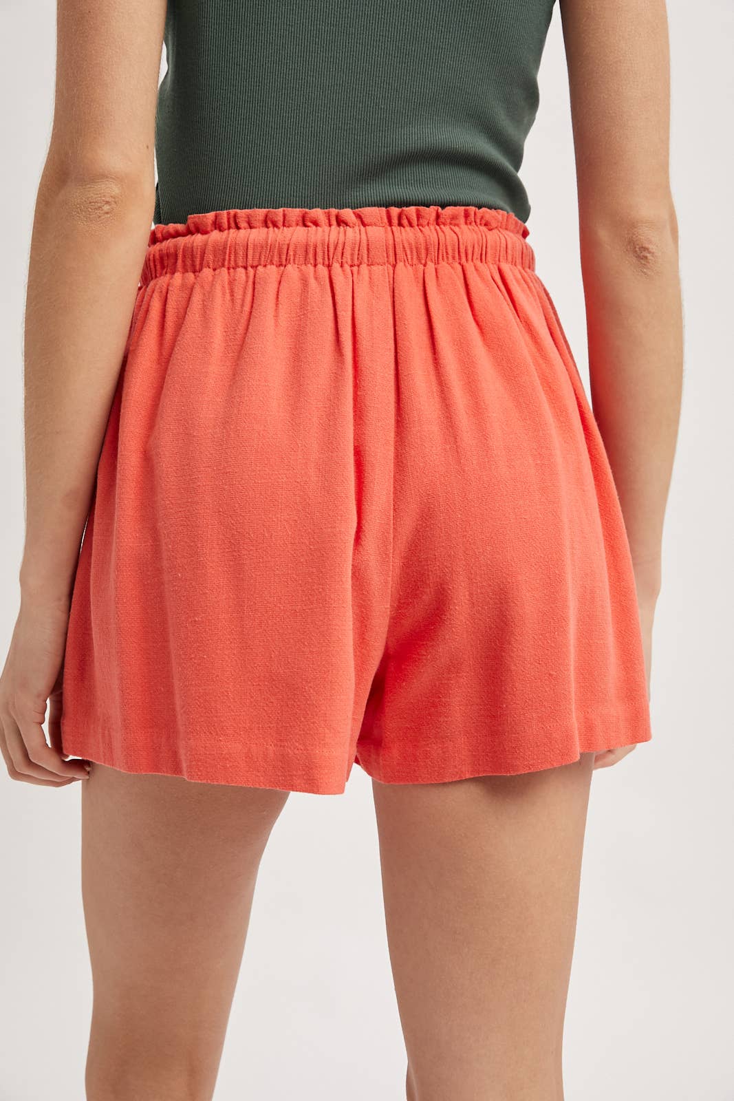 Person wearing coral shorts on a plain background