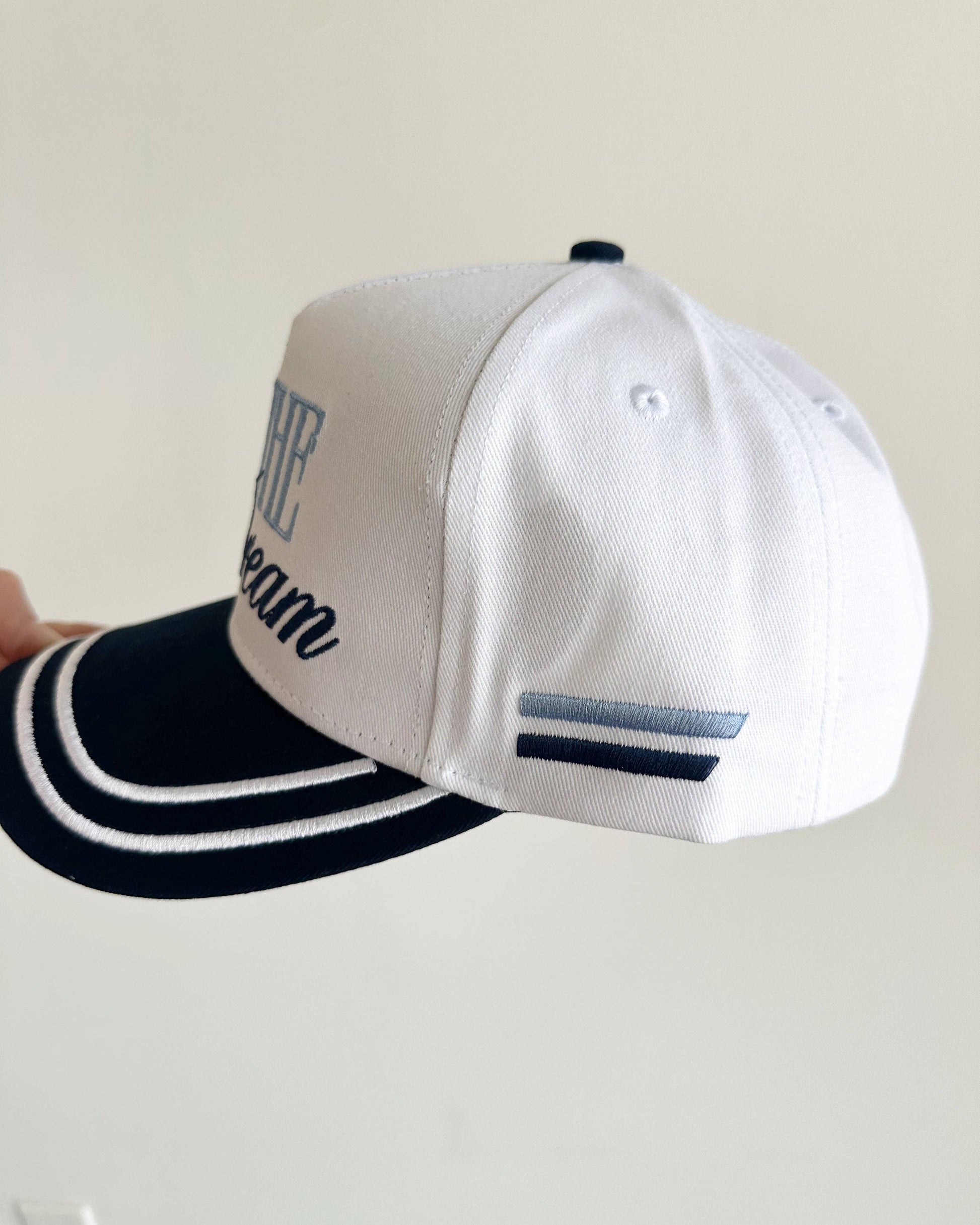 White baseball cap with light blue and dark blue accents on a light gray background