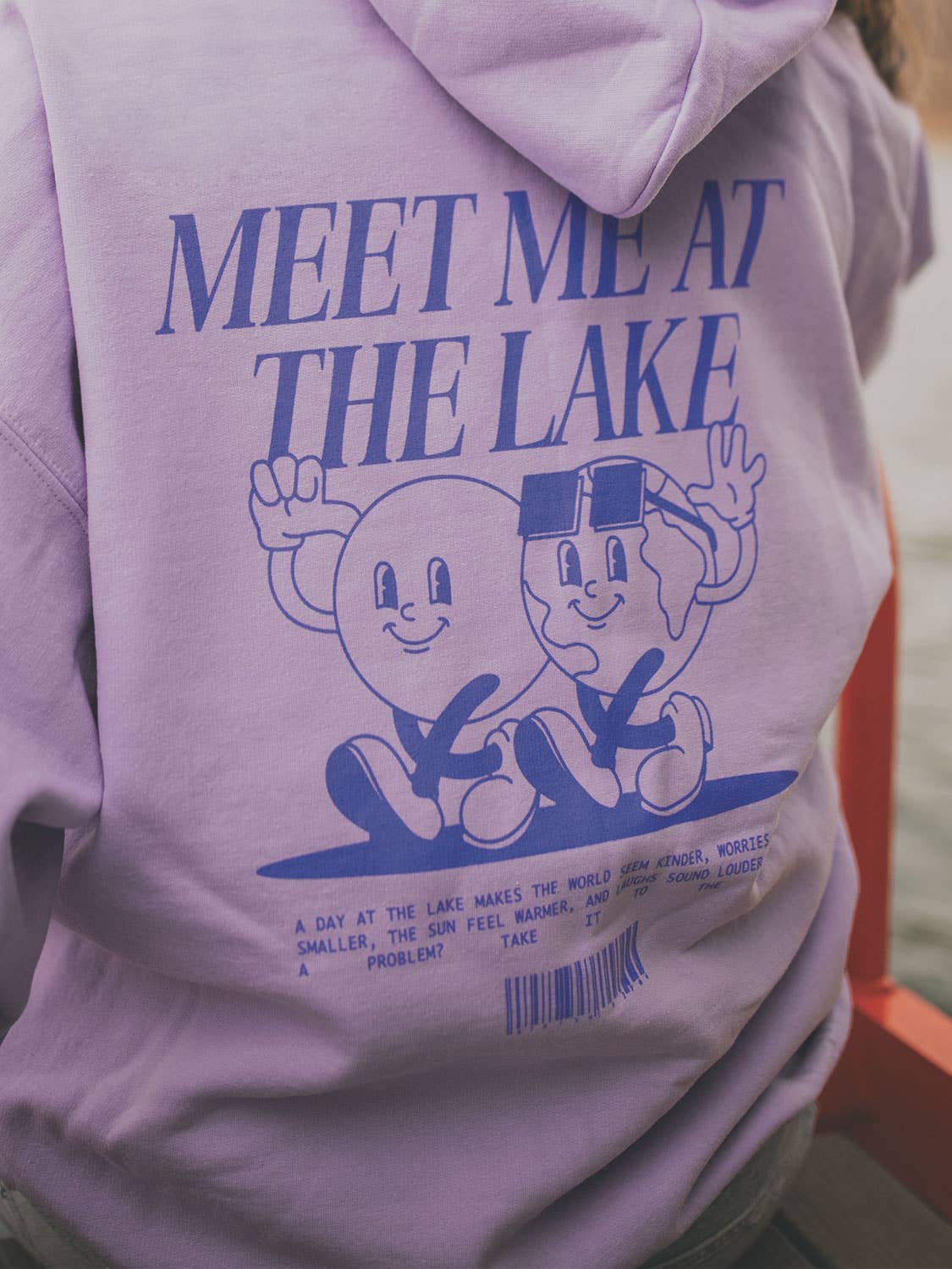 Light purple hoodie with 'Meet Me at the Lake' text and cartoon characters on the back.