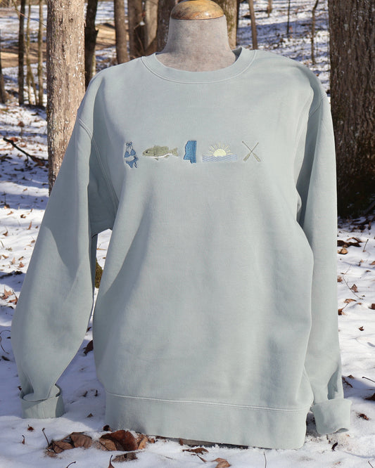 Light green sweatshirt with a lake graphic design on a mannequin in a snowy forest setting