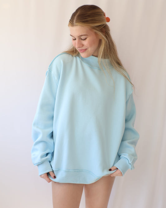 Person wearing a light blue sweatshirt on a plain background