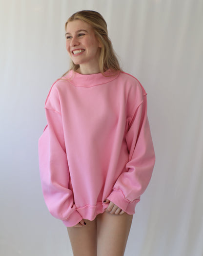 Person wearing a pink sweatshirt on a plain background