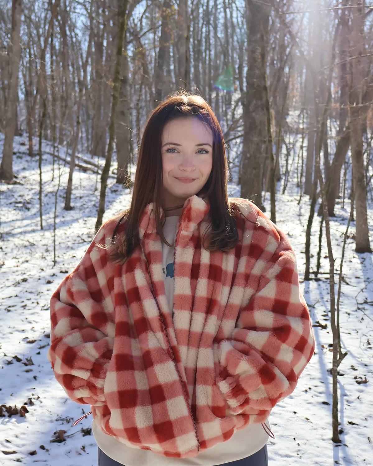Person wearing a red and white checkered coat in a snowy forest