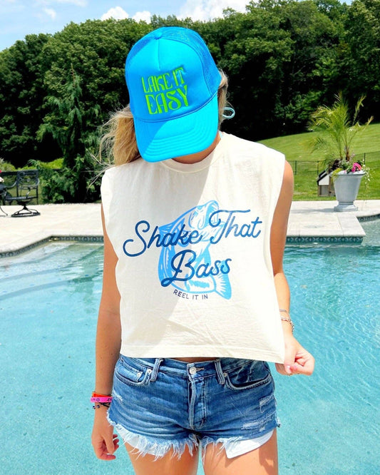 Person wearing a white sleeveless shirt with text and a blue cap by a pool