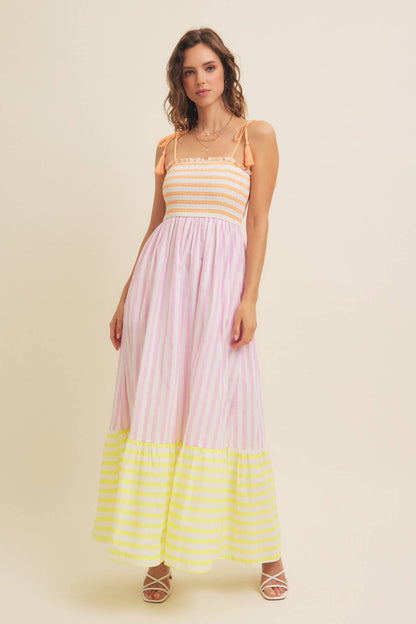 Woman wearing a striped dress with a yellow and pink color scheme on a beige background