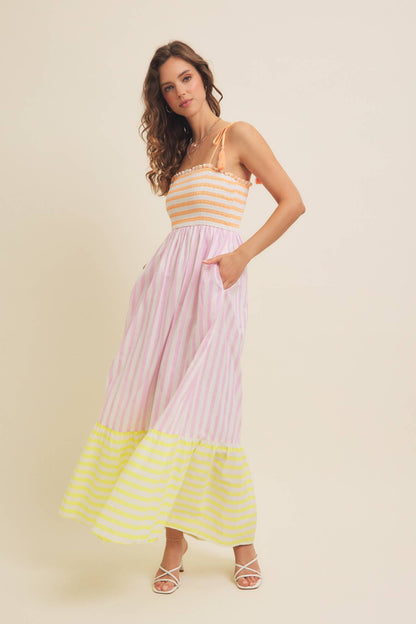 Woman wearing a striped dress with a yellow, pink, and white color scheme on a beige background