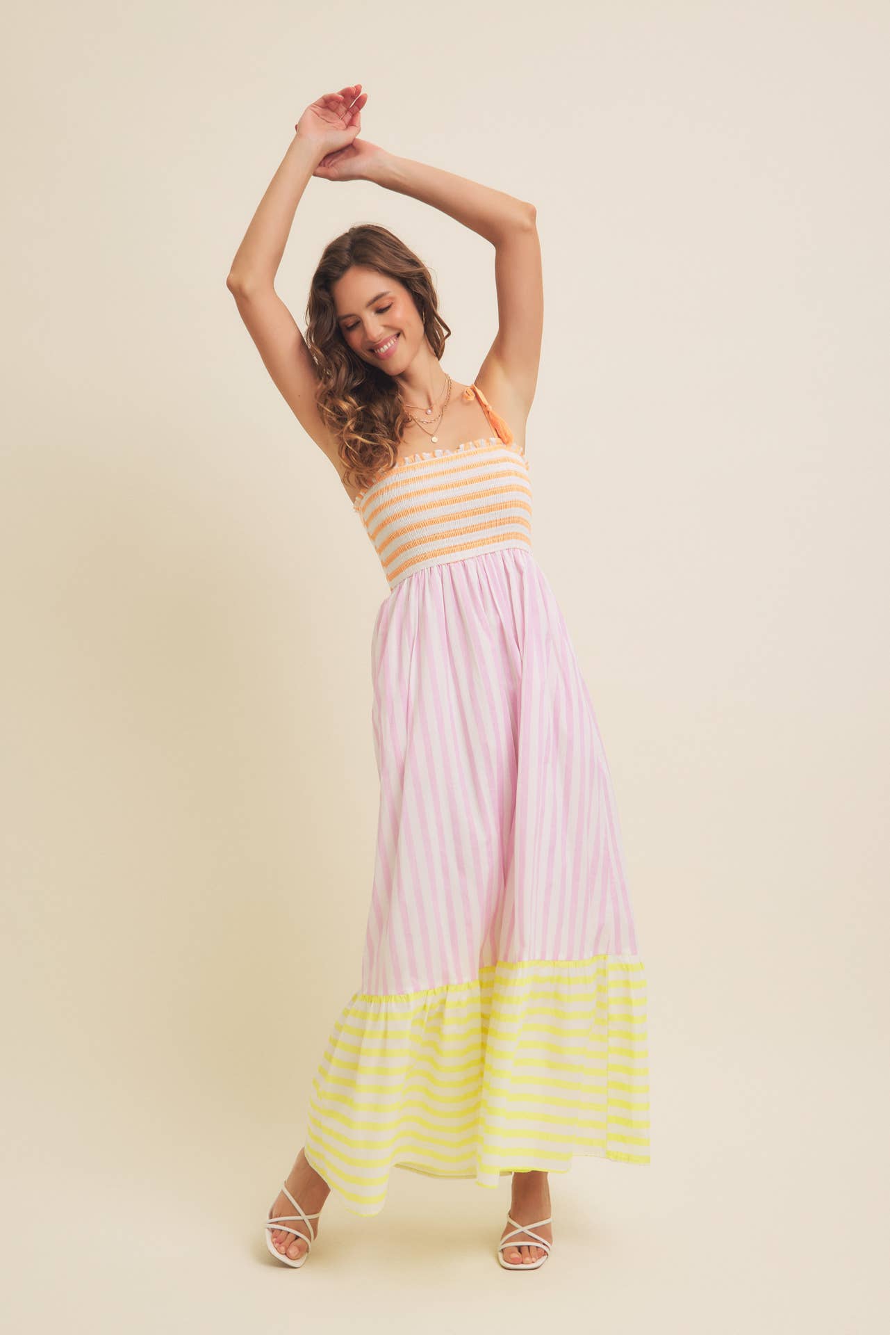 Woman wearing a colorful striped dress against a plain background
