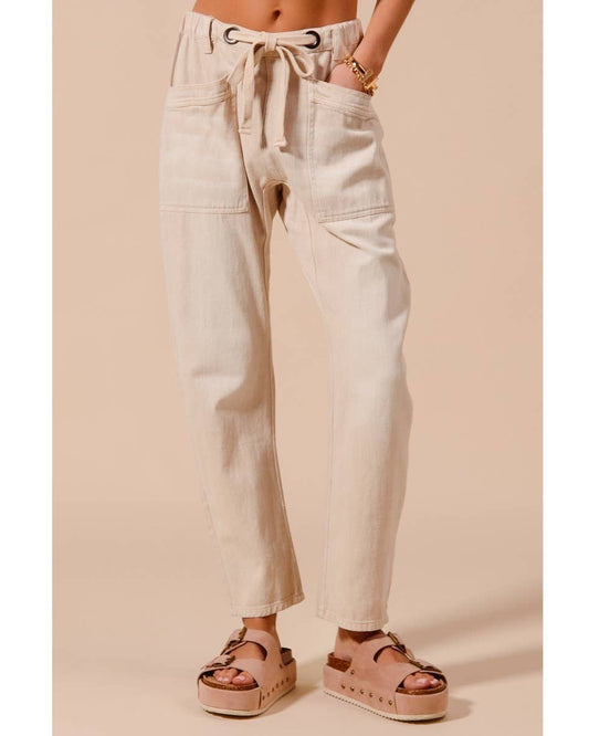 Person wearing light-colored pants and sandals on a beige background