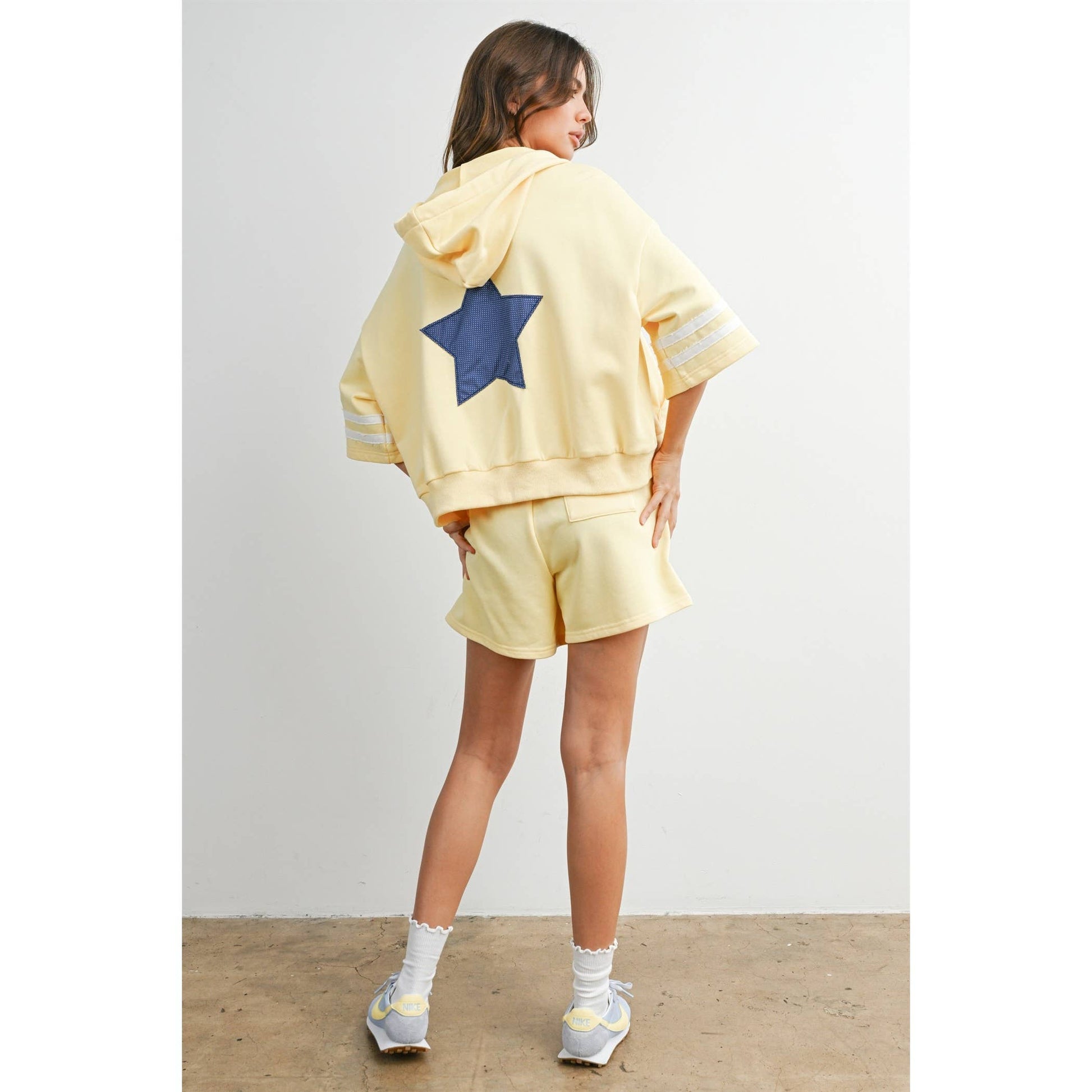 Person wearing a yellow outfit with a blue star on a plain background