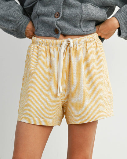 Person wearing beige shorts and a gray sweater on a plain background