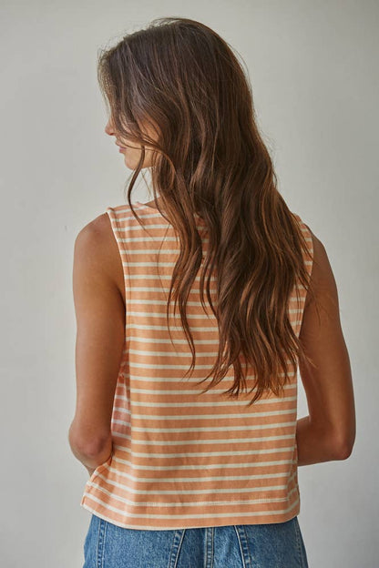 Woman wearing a striped tank top and jeans against a plain background