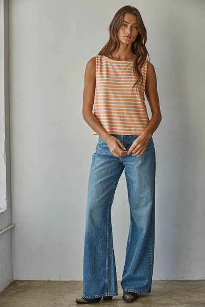 Woman wearing a striped tank top and blue jeans against a plain background
