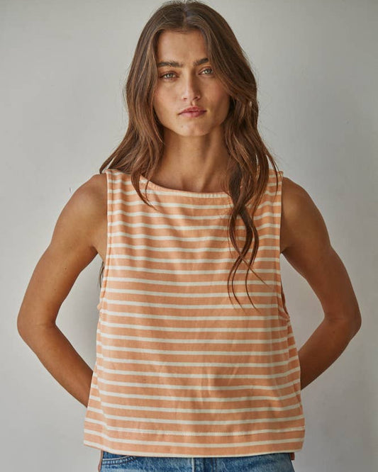Woman wearing a striped tank top and jeans against a plain background