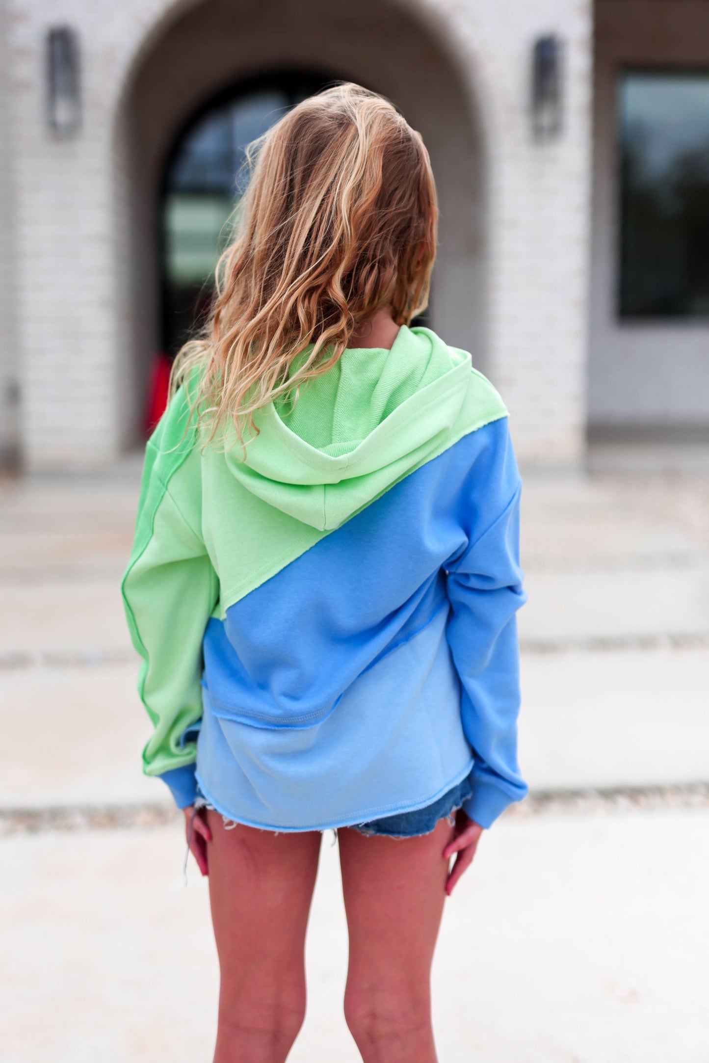 Person wearing a green and blue hoodie with a blurred background
