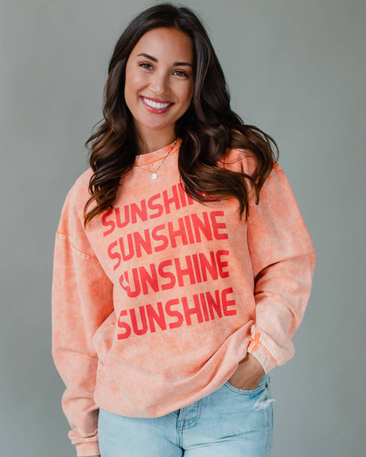 Girl wearing orange sweatshirt with 'sunshine' text