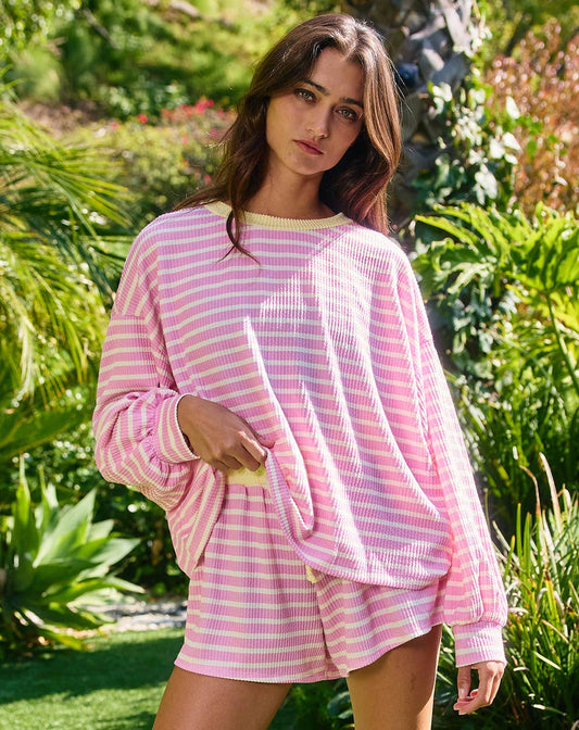 Woman wearing a pink striped outfit standing in a garden