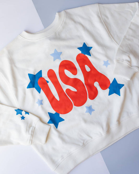 White t-shirt with 'USA' in red and stars in blue and gray on a light gray background