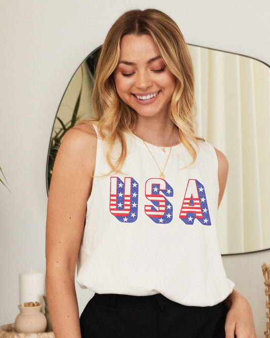 Woman wearing a white sleeveless top with 'USA' print in red, white, and blue.